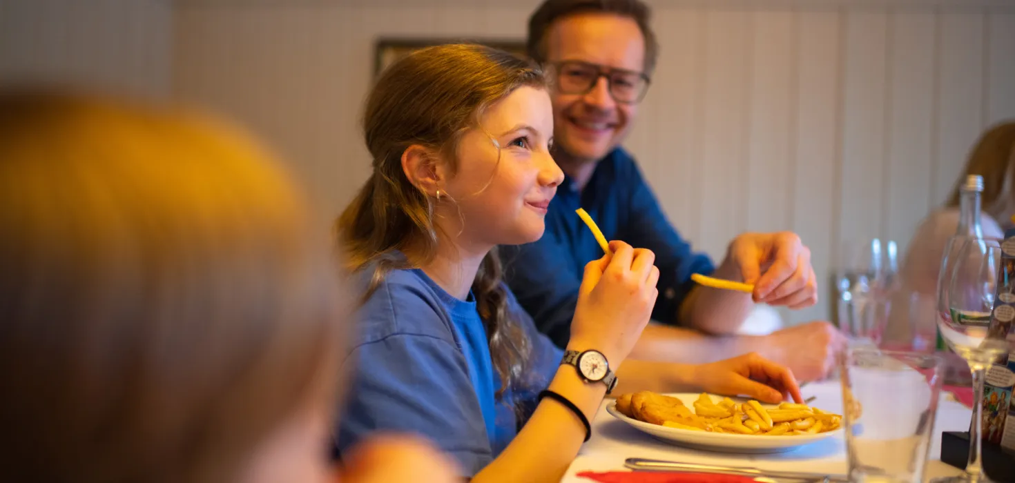 Mehrere Personen sitzen an einem gedeckten Tisch im familienfreundliche Restaurant Schwedenschenke und essen Pommes Frites