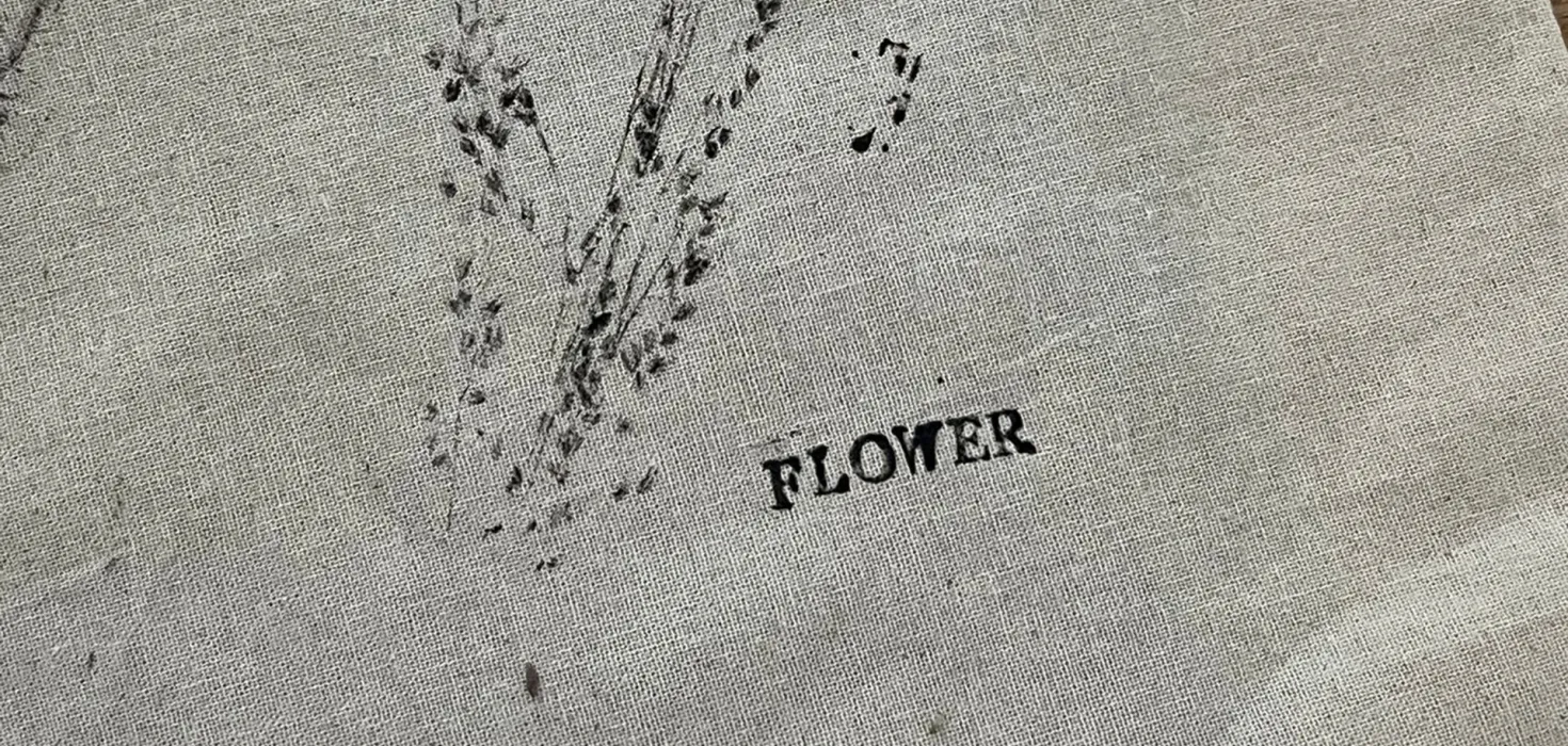 Stoff mit zartem Pflanzenabdruck in Schwarz und dem Schriftzug ‘Flower’