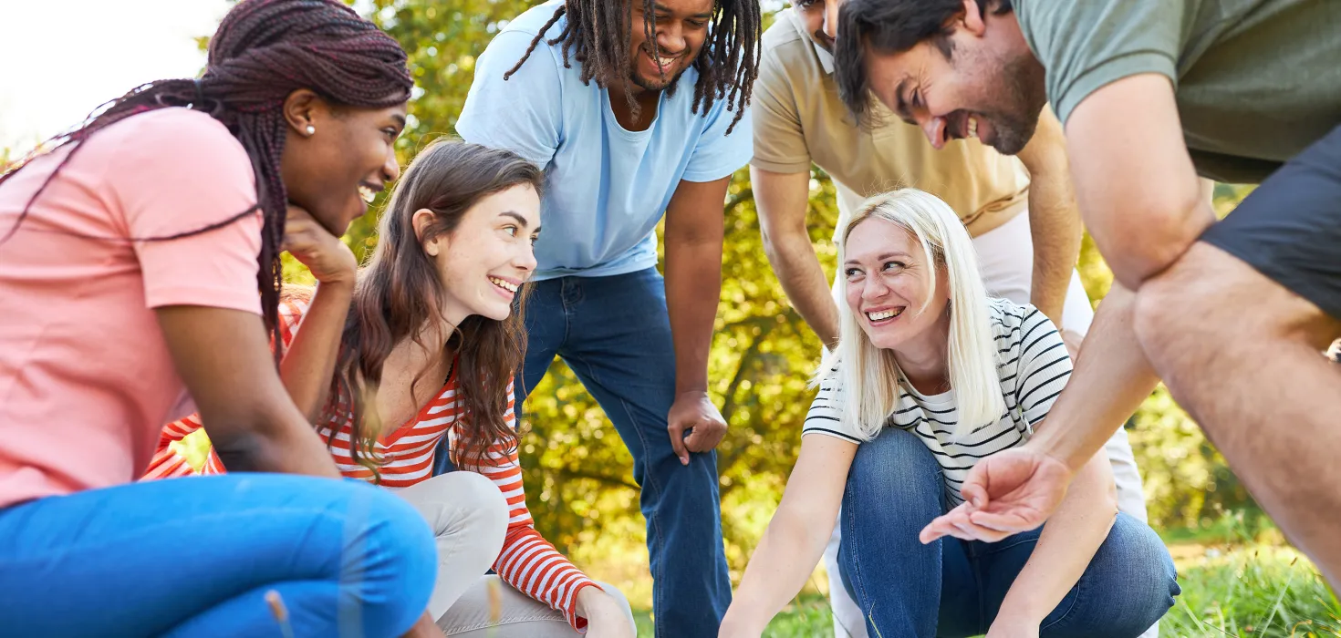 Sechs Menschen betrachten gemeinsam einen Plan auf einer Wiese