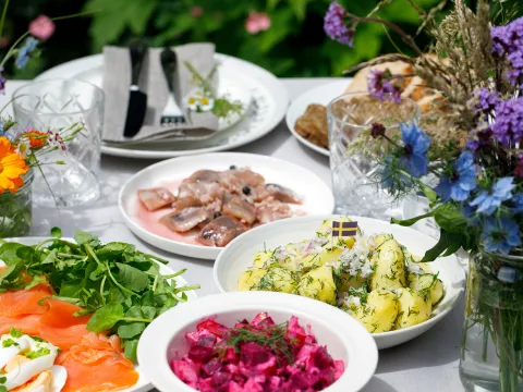 Magdalena Bujak / Adobe Stock Tisch mit verschiedenen schwedischen Gerichten und einem Sommerblumenstrauß