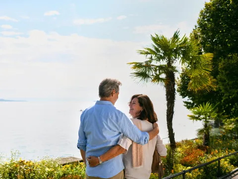 Ein Mann und eine Frau blicken auf den Bodensee im Sonnenschein