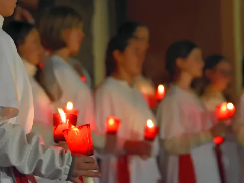 Eine Gruppe von Personen in weißen Gewändern, die Kerzen in der Hand halten