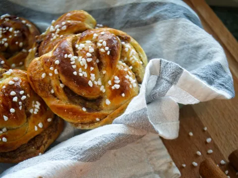 Frisch gebackene Hefeschnecken mit Hagelzucker in einem Tuch auf einem Holztisch