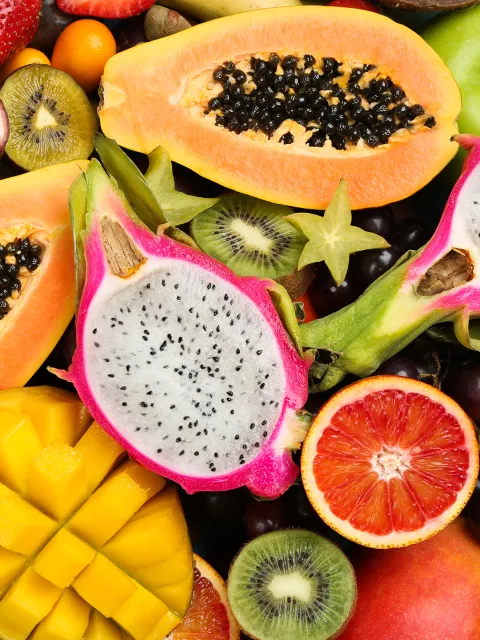 Eine Vielzahl tropischer Früchte, darunter Papaya, Drachenfrüchte, Orangen, Kiwis und Mangos, in leuchtenderen Farben und verschiedenen Formen.