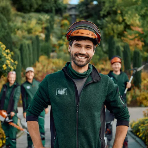 Team der Gärtnerinnen und Gärtner der Insel Mainau in Arbeitskleidung, umgeben von blühender Gartenpracht – stellvertretend für fachkundige Gartenpflege und grüne Kompetenz.