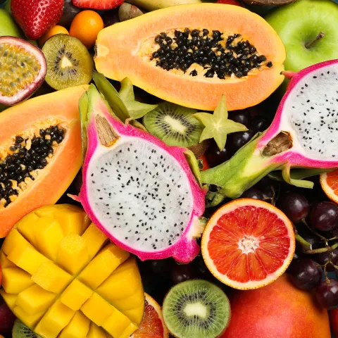 Eine Vielzahl tropischer Früchte, darunter Papaya, Drachenfrüchte, Orangen, Kiwis und Mangos, in leuchtenderen Farben und verschiedenen Formen.